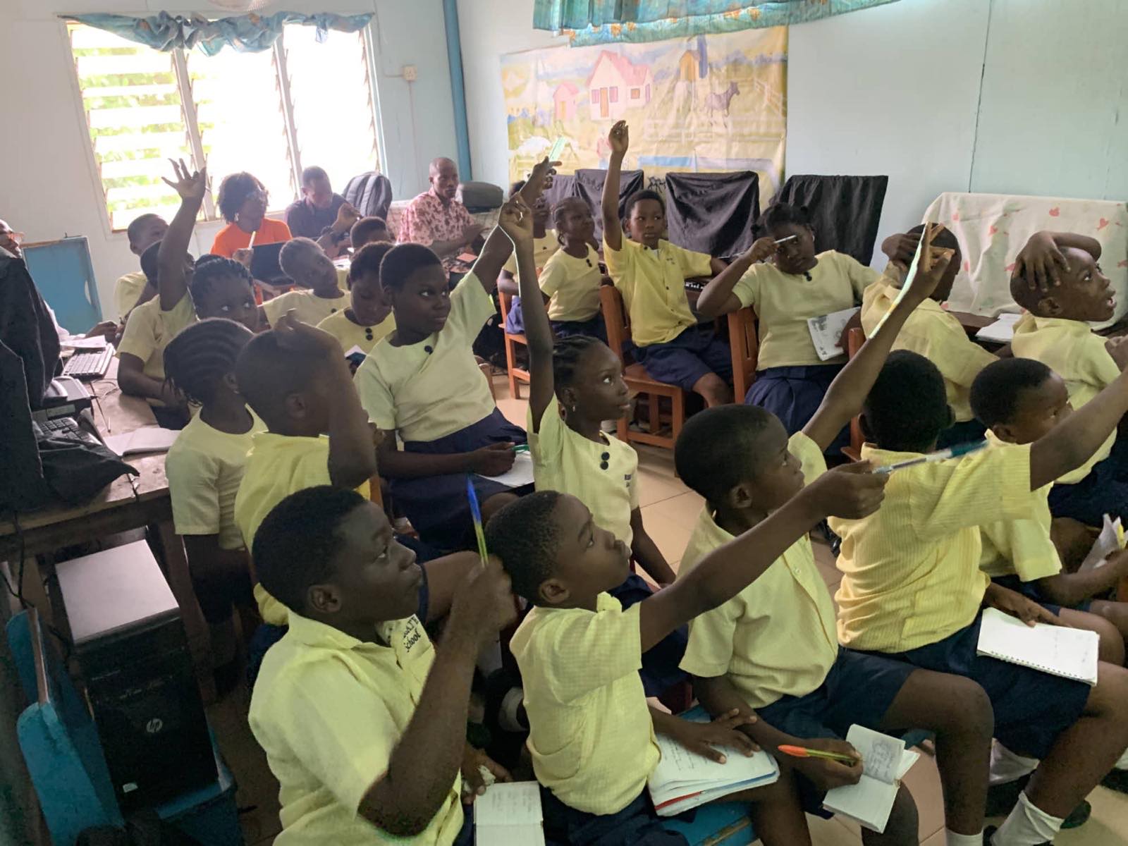 A class at their desks with hands raised
