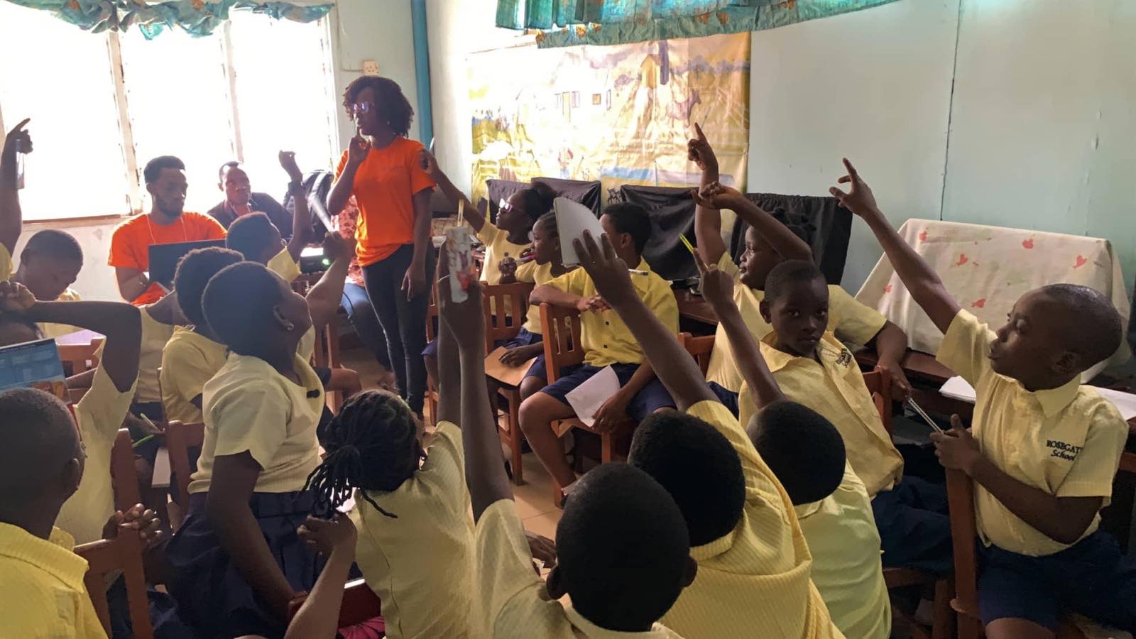 A volunteer leading a hall of pupils with their arms raised